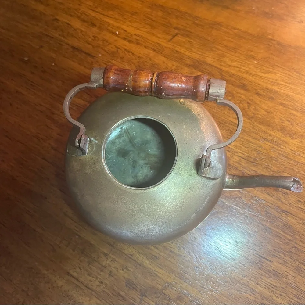 antique brass kettle with a wooden handle and three-legged base.